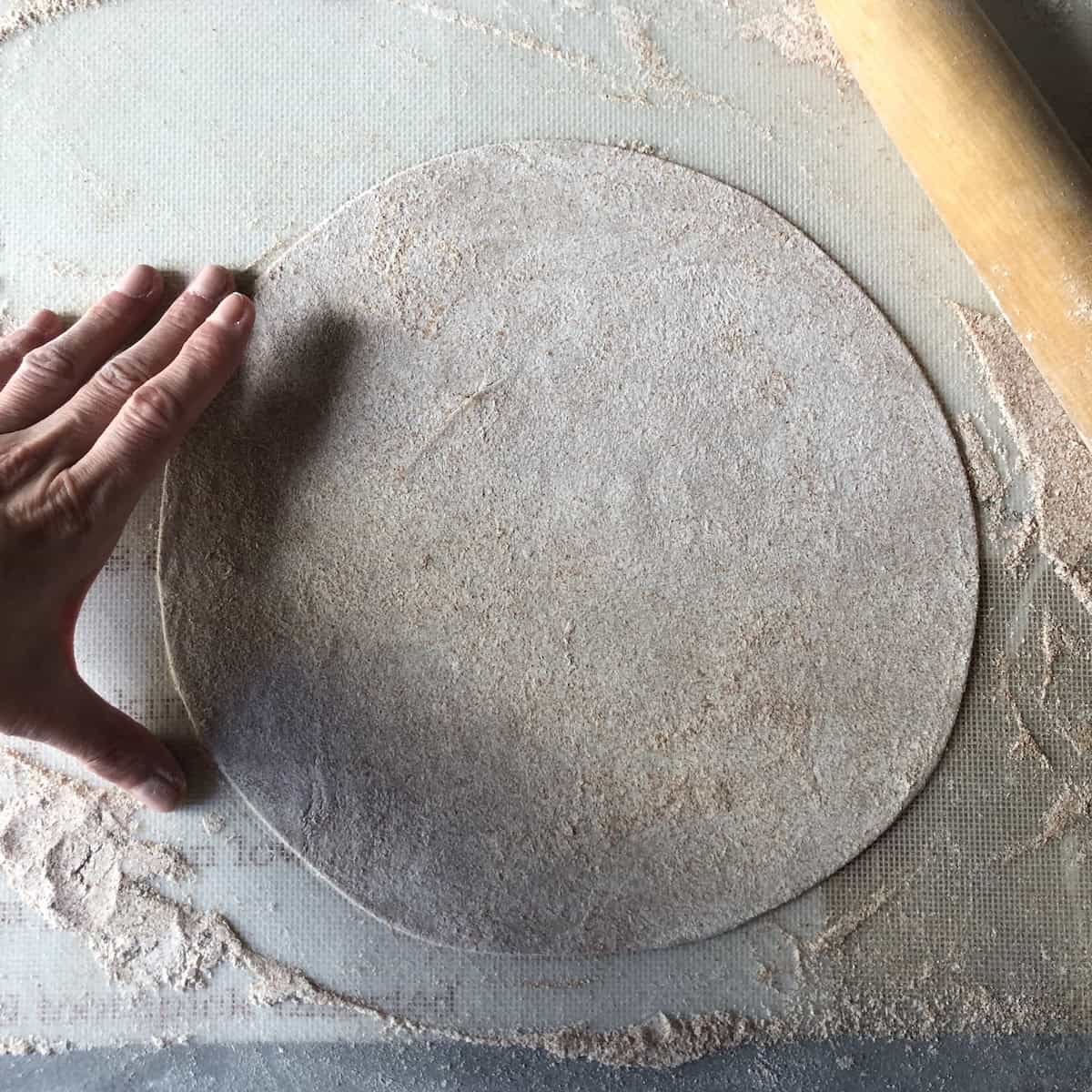 Perfectly rolled thin whole wheat St. Louis style pizza dough circle ready for toppings - homemade no yeast pizza crust recipe with crispy results.
