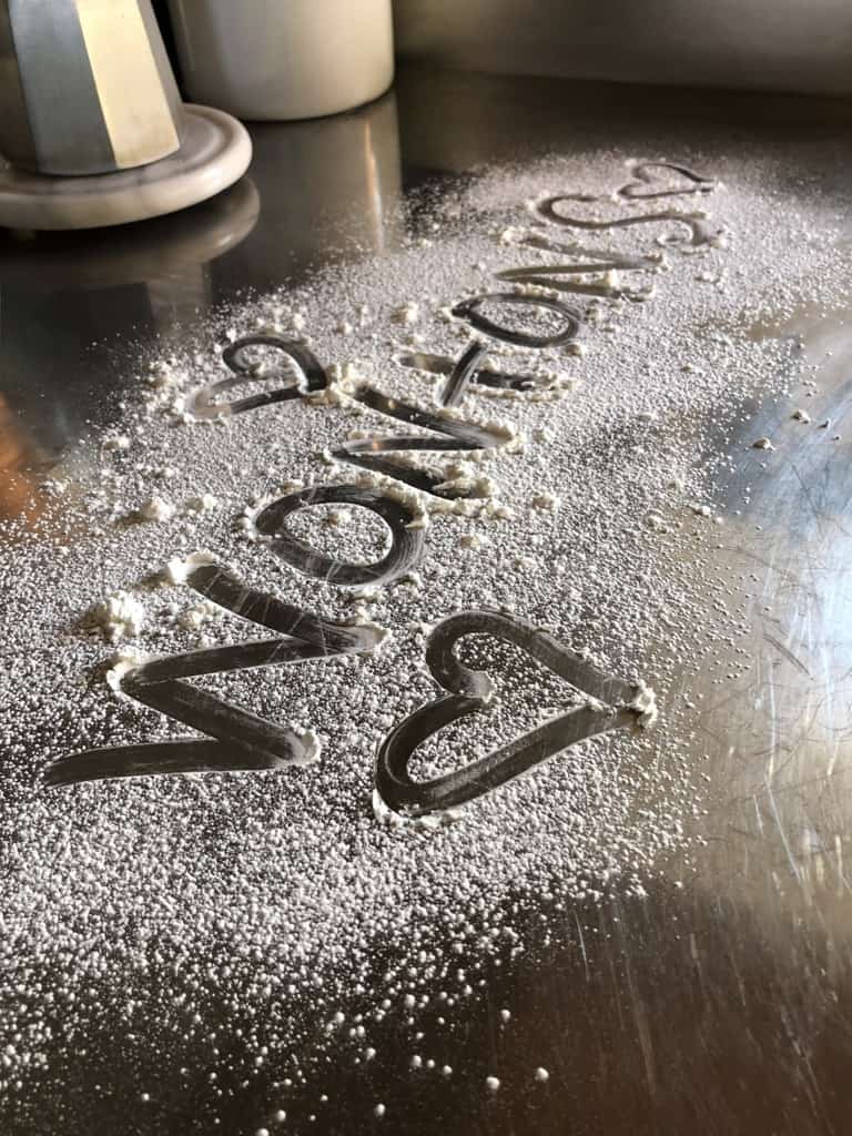 cornstarch sifted onto stainless steel countertop with the words "WONTONS" and hearts drawn using my finger.