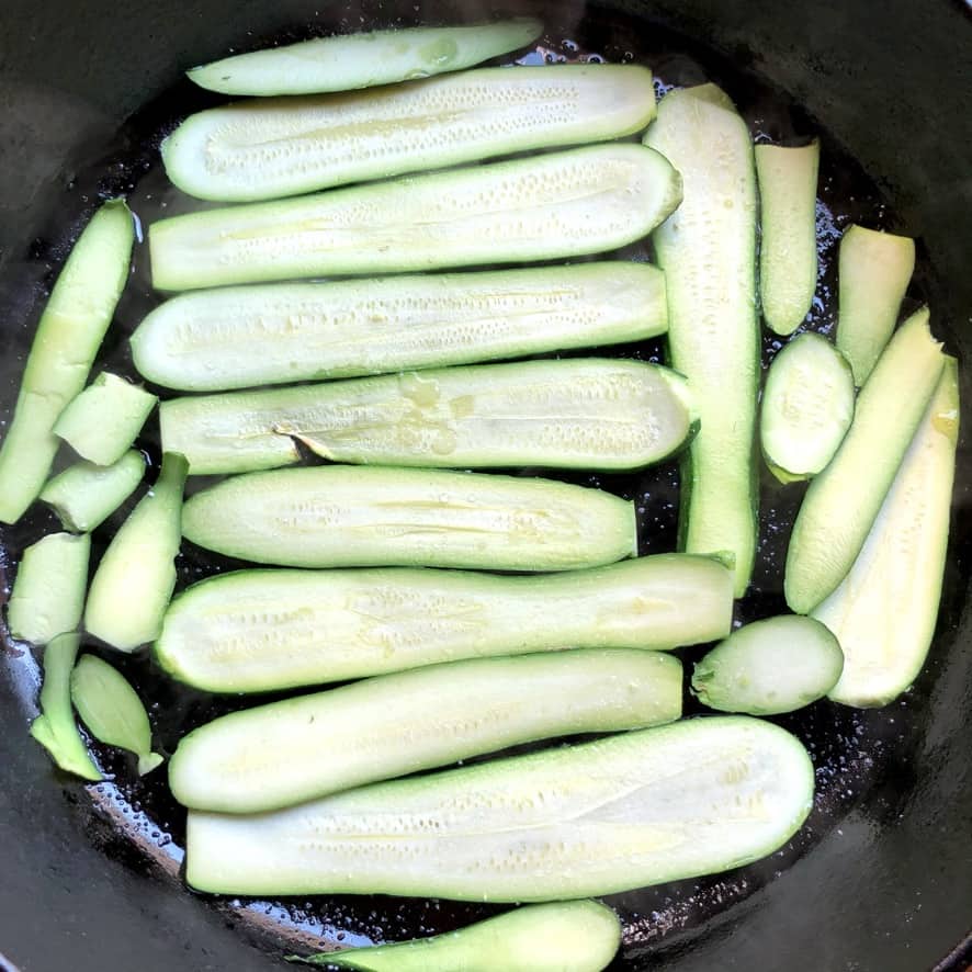 long thinly sliced zucchini in a cast iron skillet