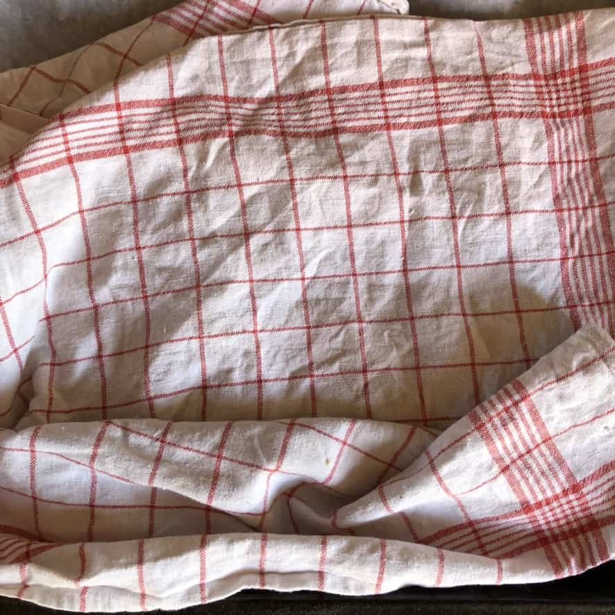 a red and white striped kitchen towel covering the top of the resting wonton dough