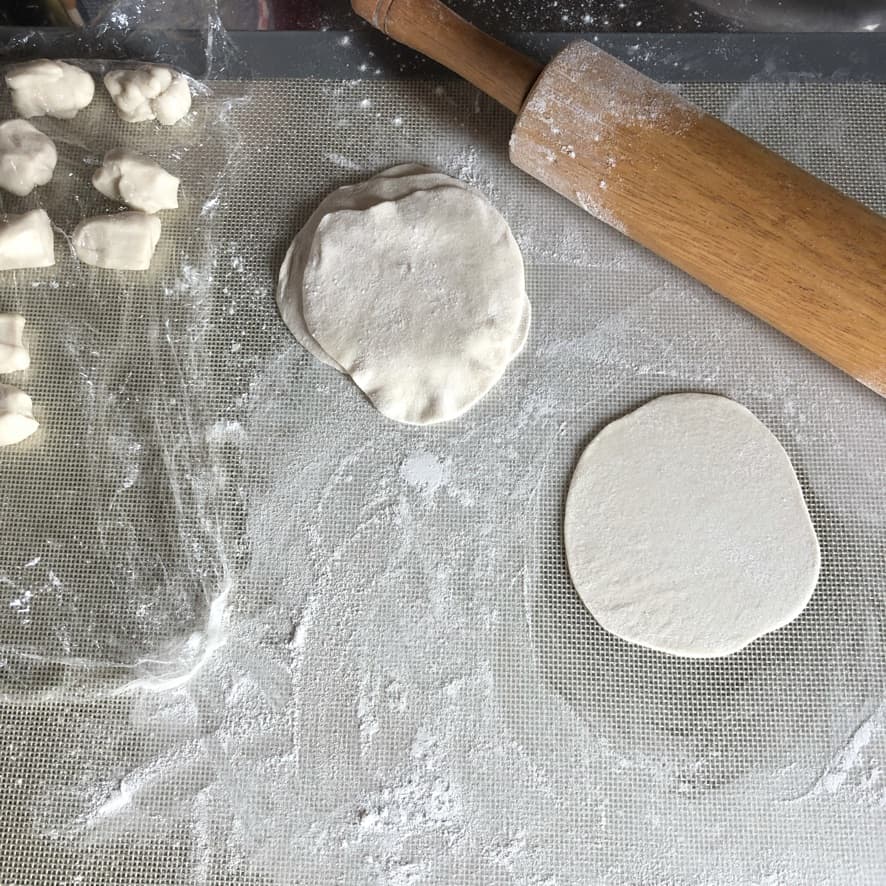 rolling out homemade dumpling dough on a lightly floured surface