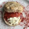a beautiful slightly pink'ish with strawberry flecks scone that's been split in half, clotted cream added, topped with homemade strawberry jam and the plate sprinkled with freeze-dried strawberry powder with strawberry coulis dots off to the side