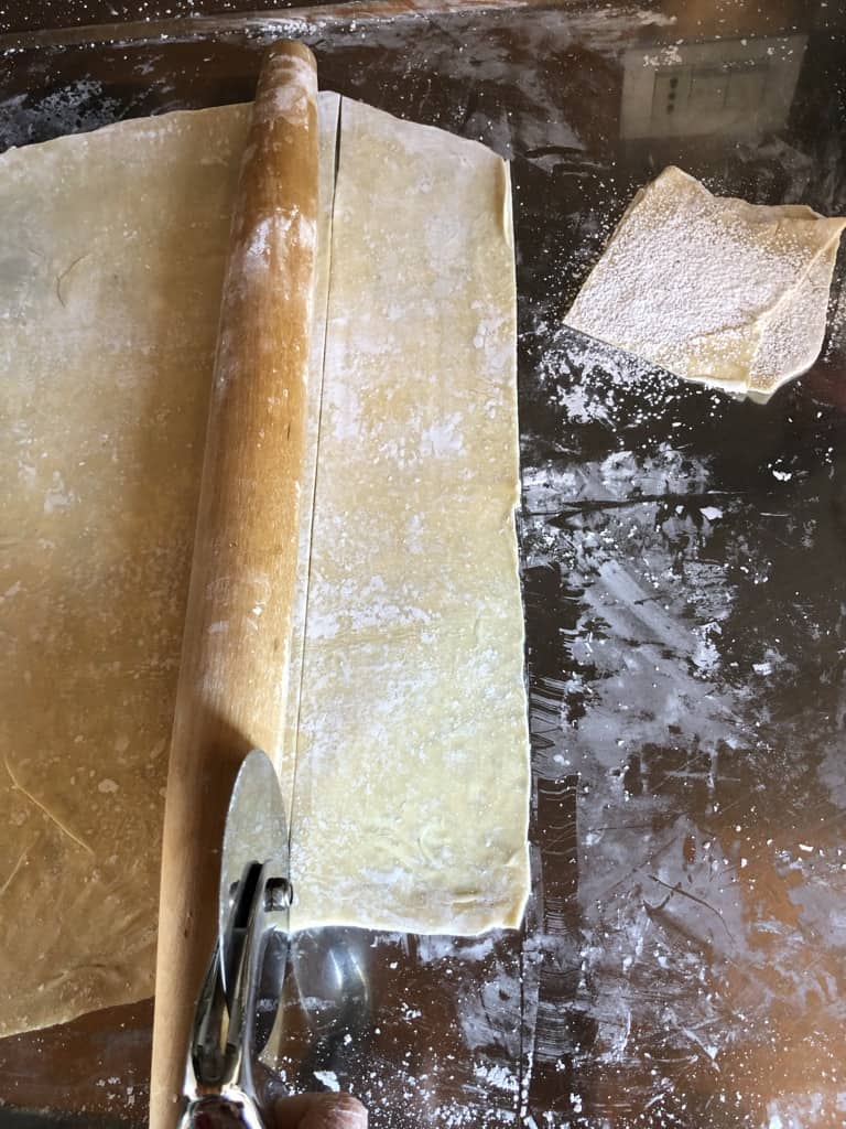 using the rolling pin as a guide to cut straight lines to make squares of wonton wrappers