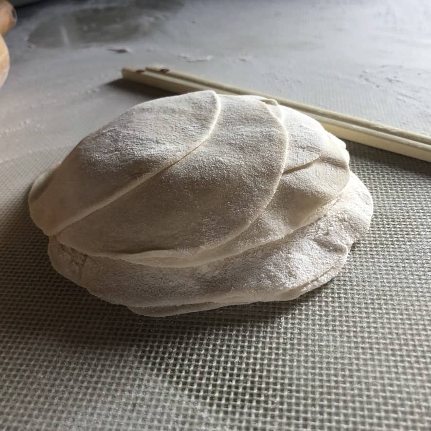 dumpling dough wrappers freshly rolled out and a pair of chopsticks in the background