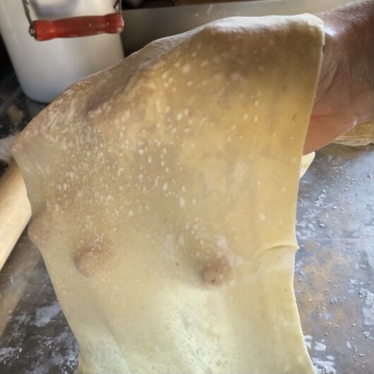 my hand holding up the final rolled out wonton dough to show that you can actually see through the dough when it's been rolled properly