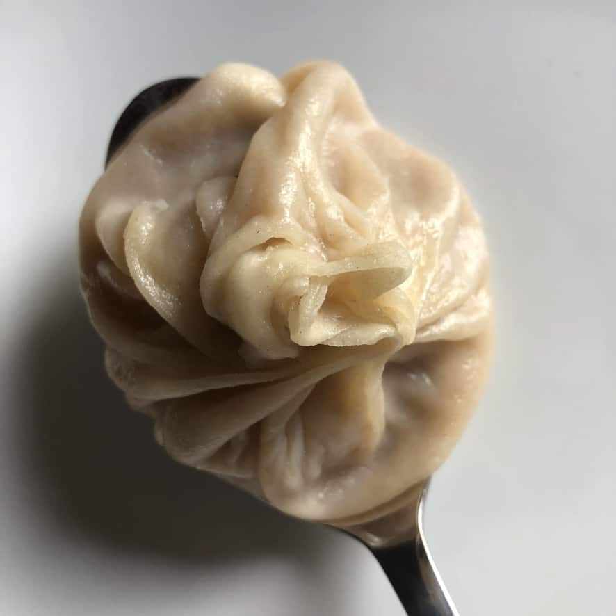 homemade chinese soup dumpling resting on a spoon