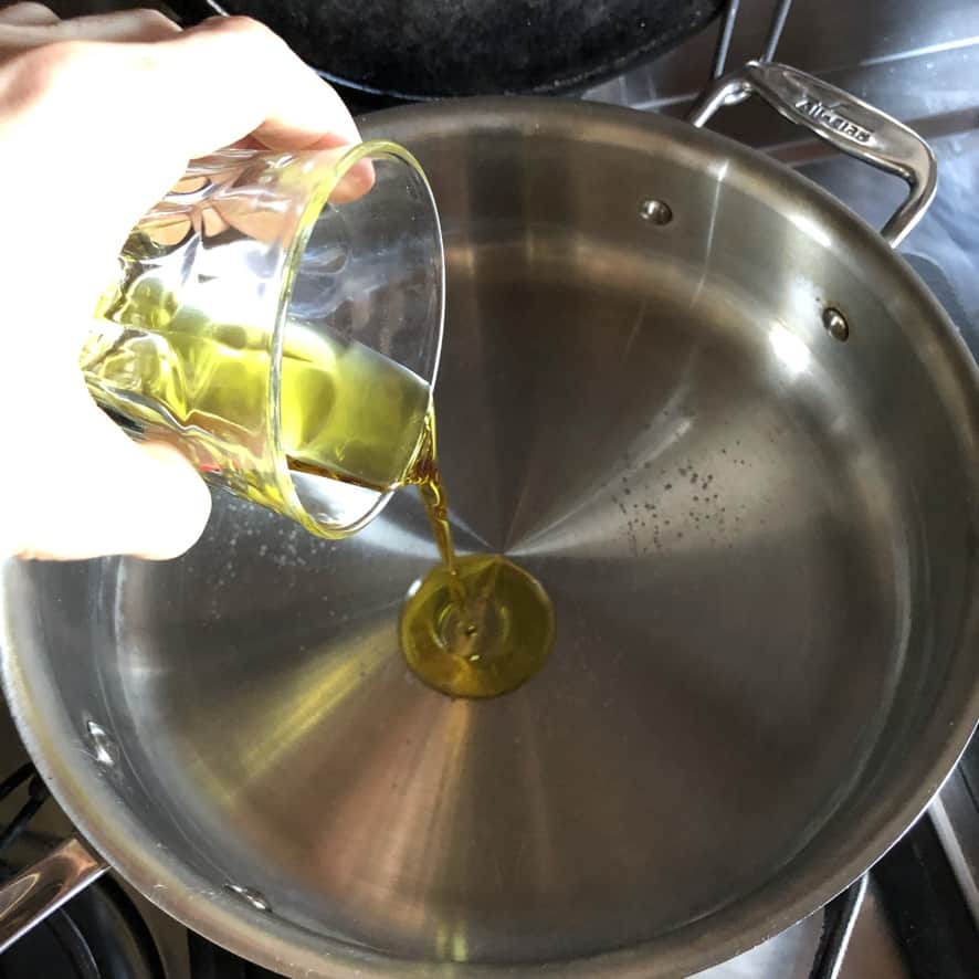 pouring olive oil into a saute pan