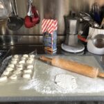 balls of dough and a rolling pin rolling out one ball on a countertop
