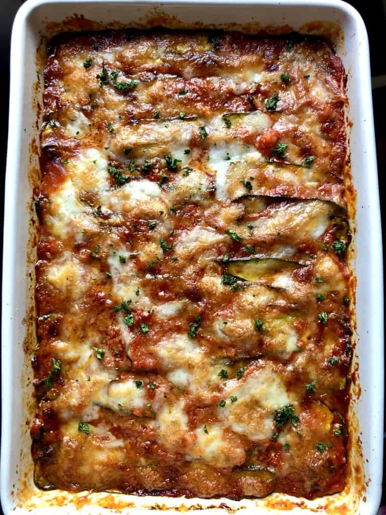 a bubbly ooey gooey cheesy golden brown eggplant and zucchini parmigiana in a white ceramic lasagna dish