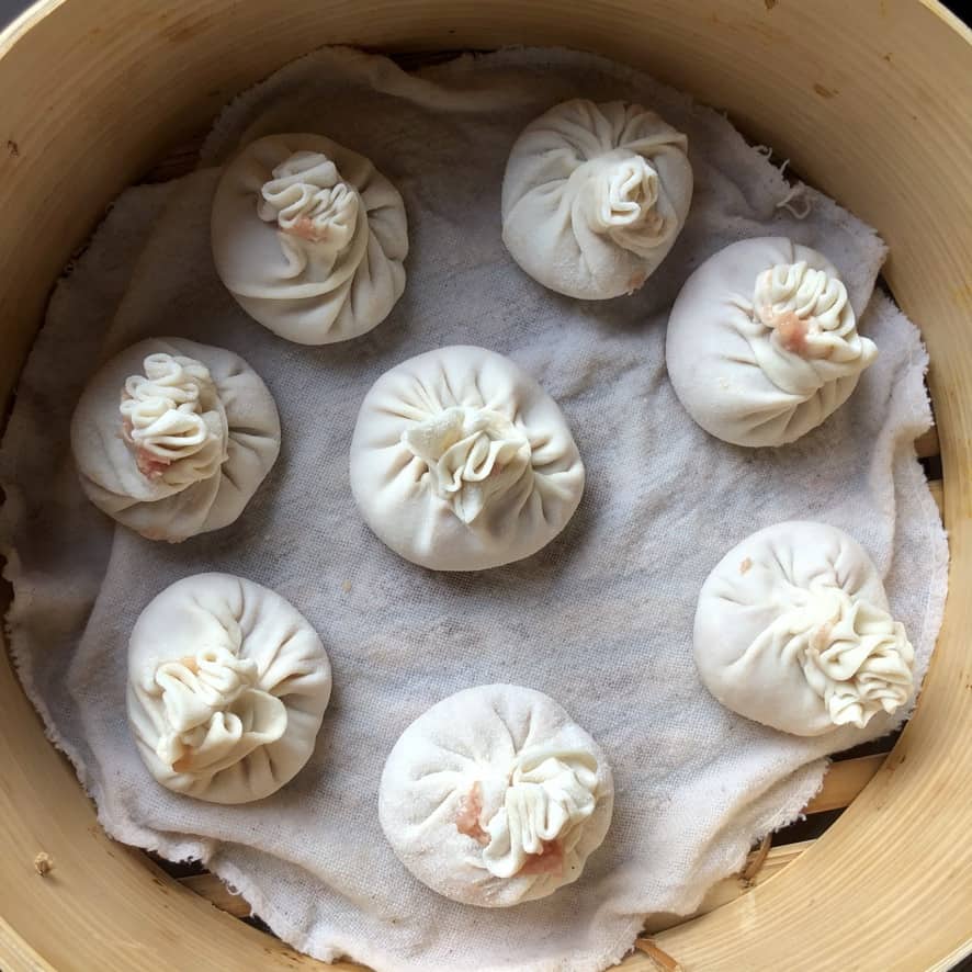 raw chinese soup dumplings in a bamboo basket