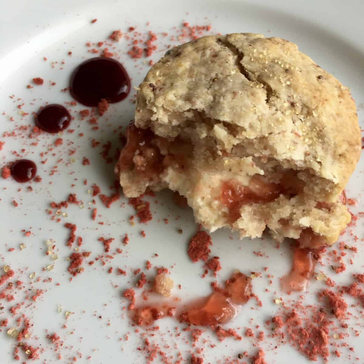 The most delicious homemade strawberry scone with half of it eaten revealing the tender crumb inside