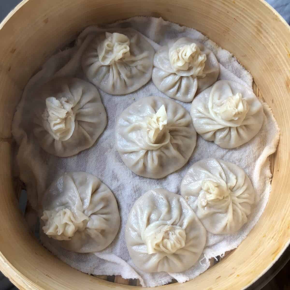 the best homemade chinese soup dumplings xiaolongbao (小笼包) just steamed and still sitting in the bamboo steamer