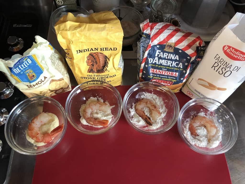 all four bags of flour and cornmeal with respective prep bowls holding a single shrimp each in front of each bag