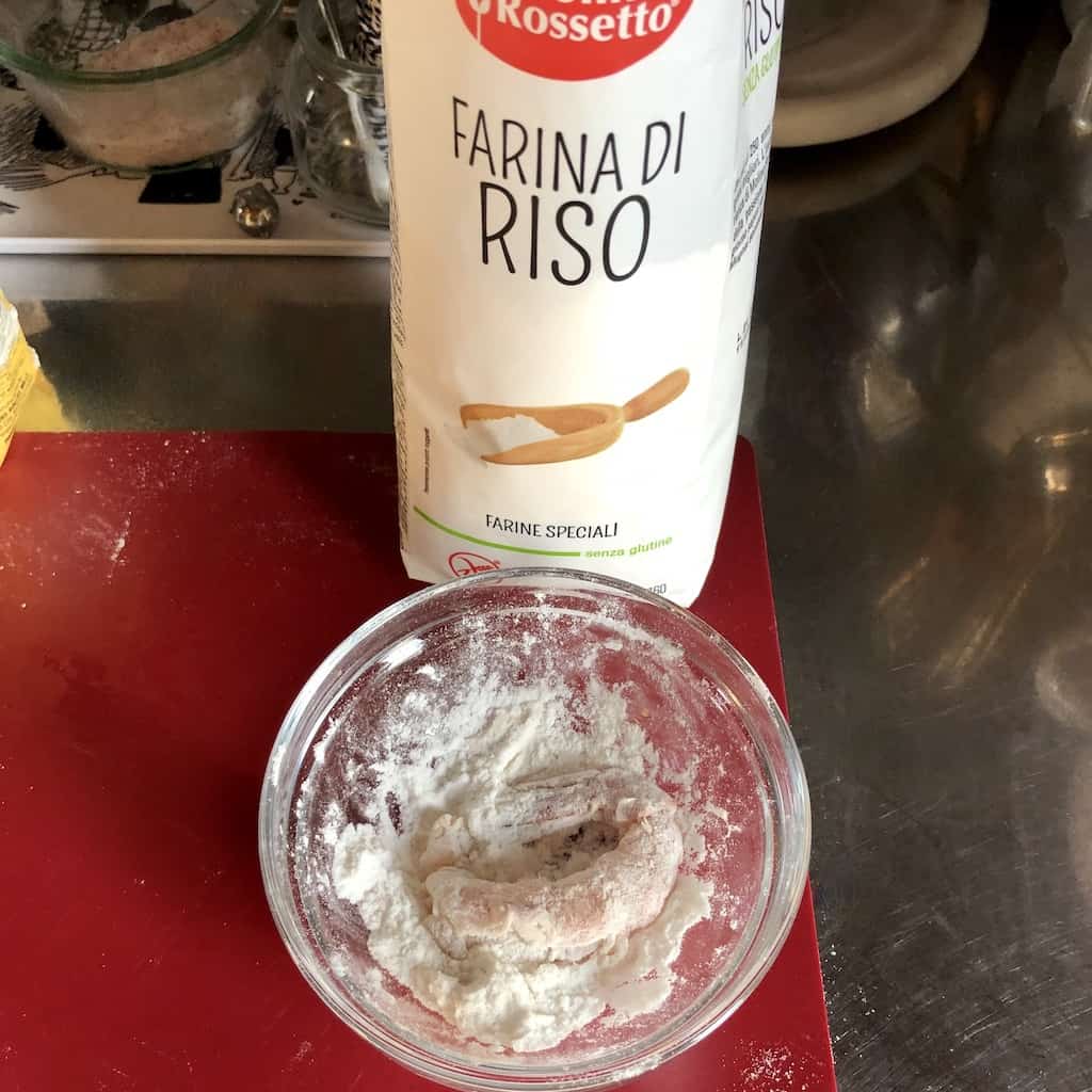 an Italian bag of rice flour with a small glass prep bowl containing a shrimp in some of the flour in front of the bag