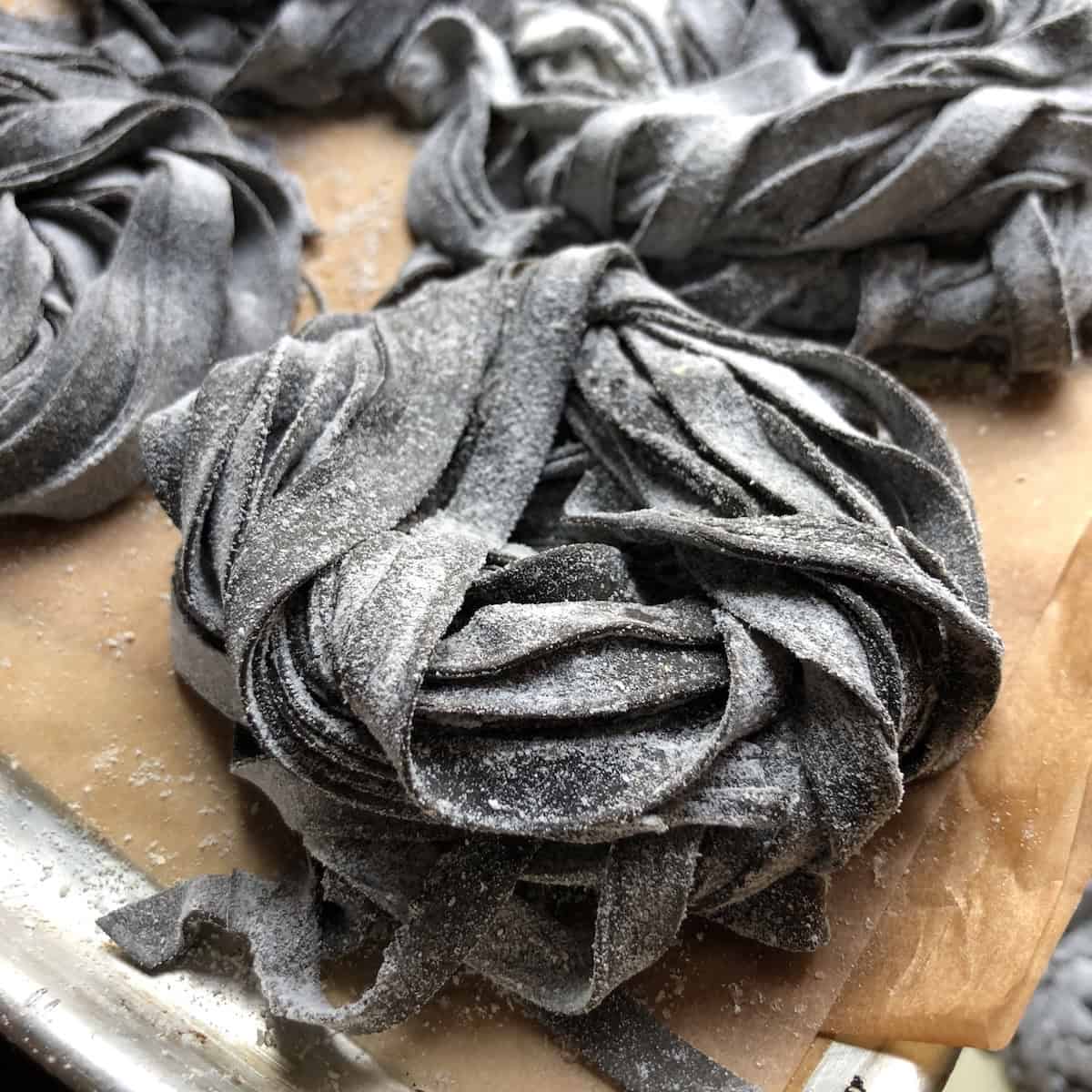 Black fettuccine squid ink noodles formed into nests ready to cook or freeze for long term storage, homemade fresh squid ink pasta.