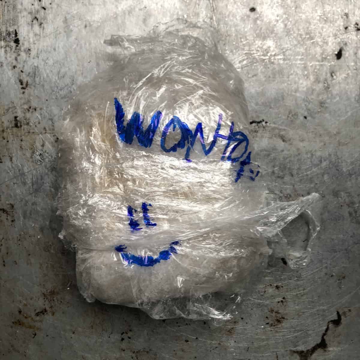 A stack of homemade wonton wrappers wrapped in cling film and labeled ready to freeze or refrigerate
