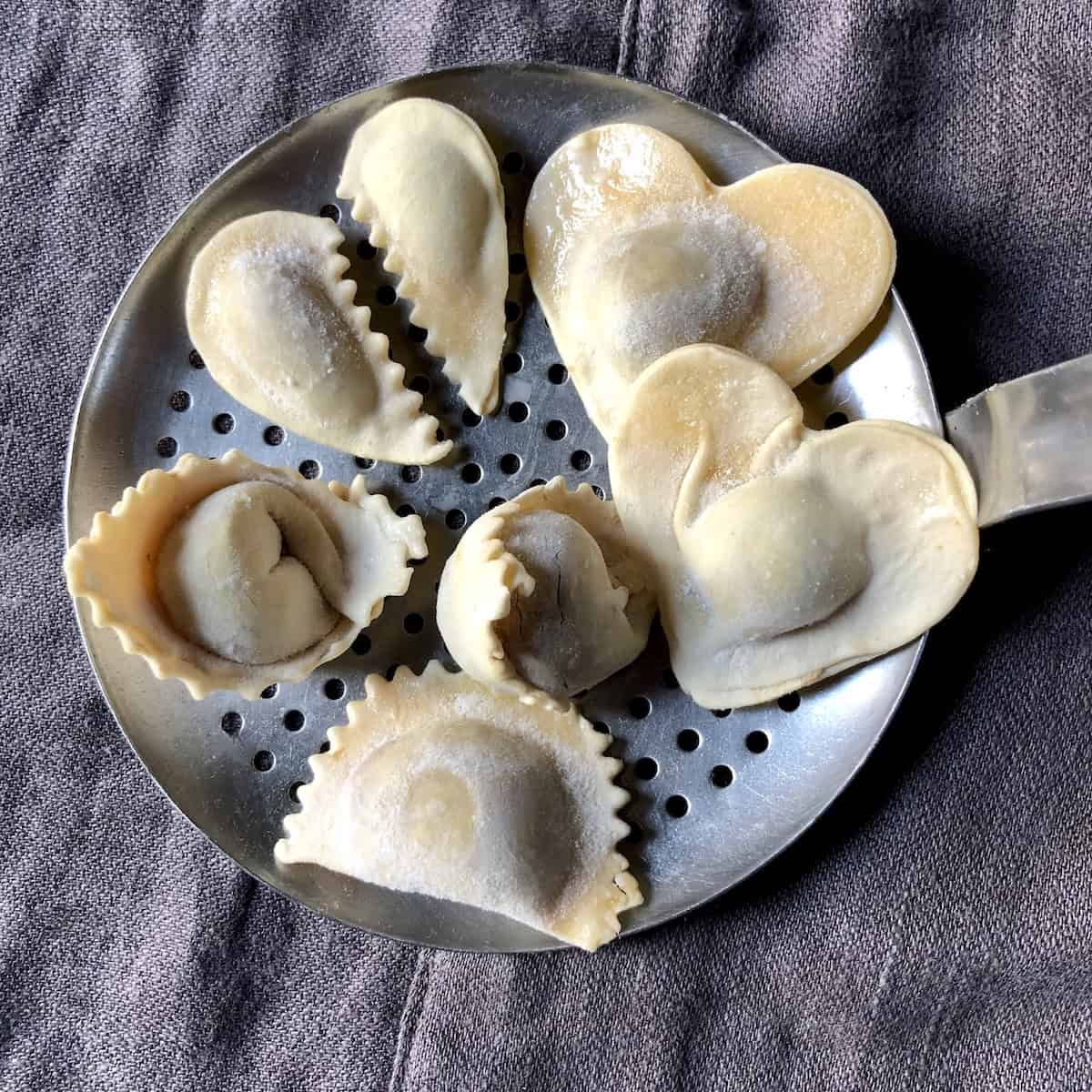 Homemade Sichuan pork and ginger wontons shaped into hearts including full hearts and broken hearts, pork wonton recipe with red oil chili sauce.