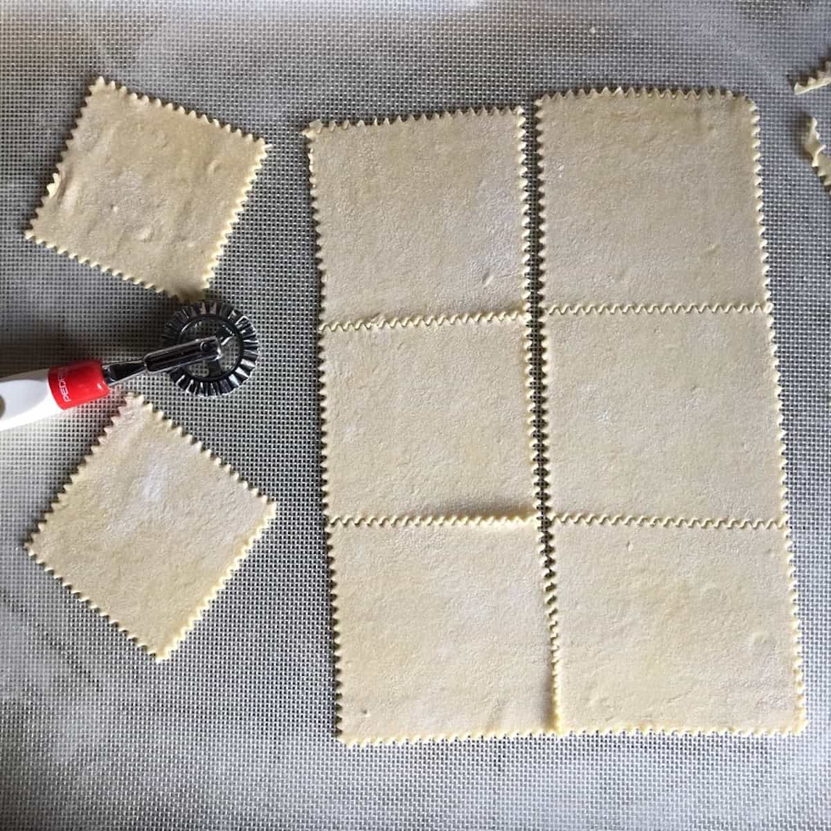A pasta bike next to homemade bread flour wonton wrappers cut with zigzag edges, wonton wrappers you can make at home with different flours.