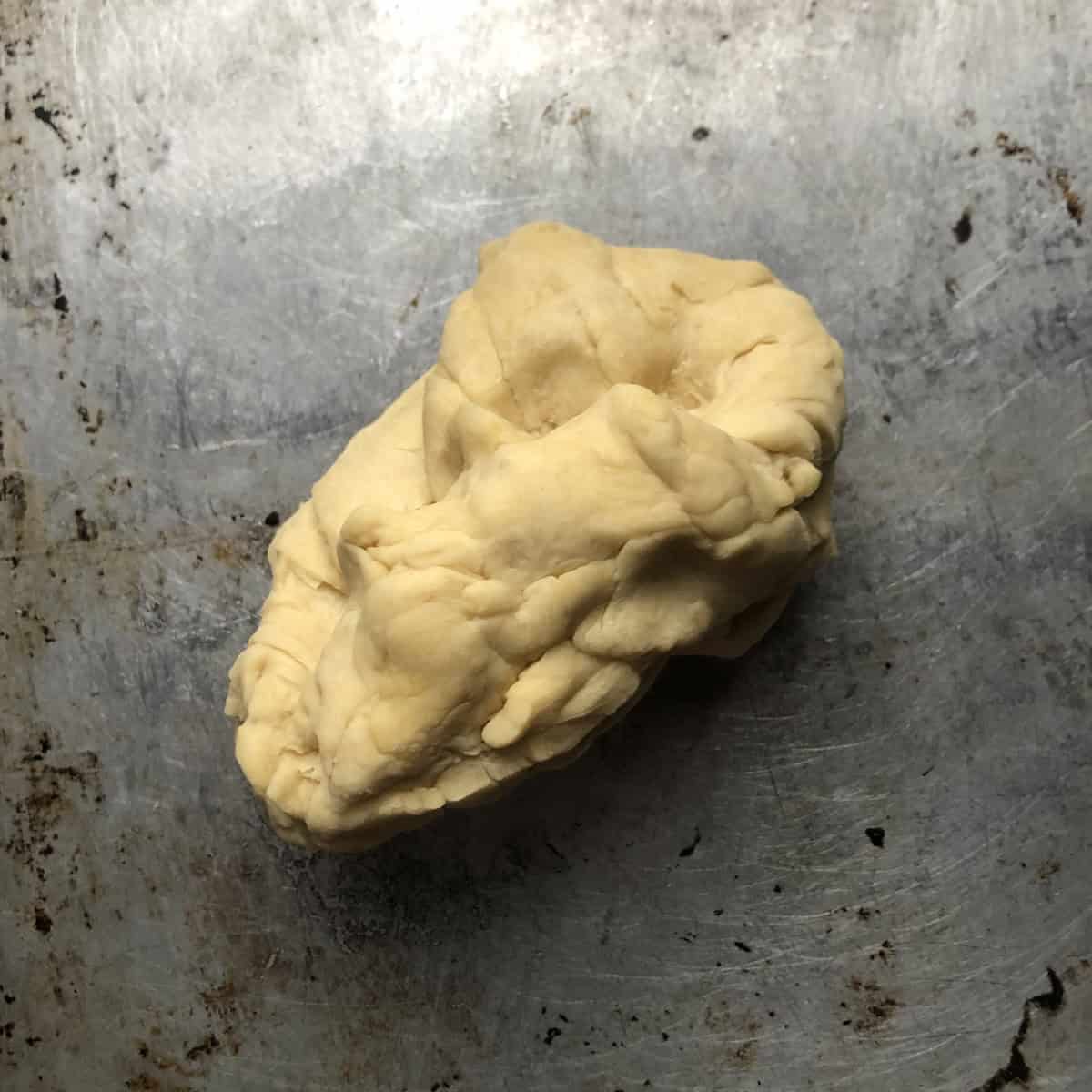 Wonton wrappers recipe dough after adding water to form a stiff dough, how to make wonton wrappers that are sturdy and will hold fillings and allow you to shape them without weeping - showing what wonton dough looks like before kneading.

