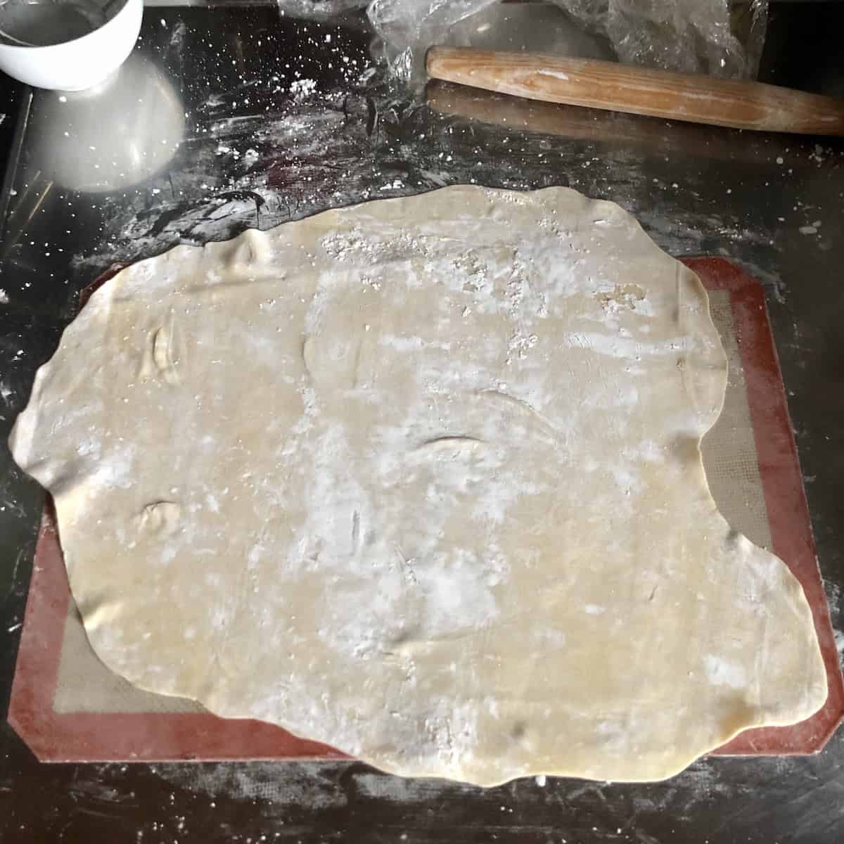 Wonton wrapper dough rolled thin to one-eighth inch thickness on a cornstarch-dusted surface, how to make wonton wrappers paper thin at home.