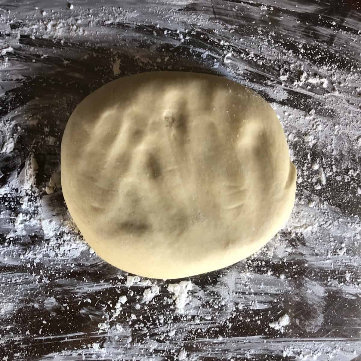 Portioned wonton wrapper dough patted down flat and ready to roll out, make wonton wrappers from scratch by rolling the dough thin.
