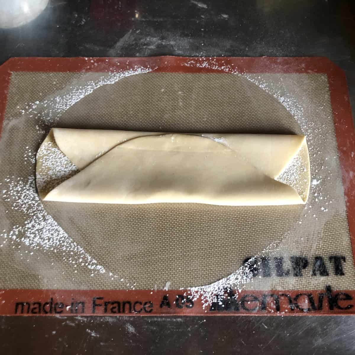 Wonton wrapper dough folded like a letter and ready to be wrapped in cling film to rest for 30 minutes, wonton wrapper ingredients coming together.
