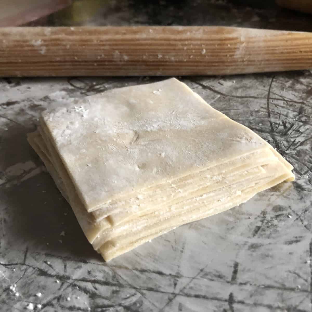 A stack of perfect homemade wonton wrappers dusted with cornstarch, wonton wrappers recipe for dumpling wrappers you can make from scratch.