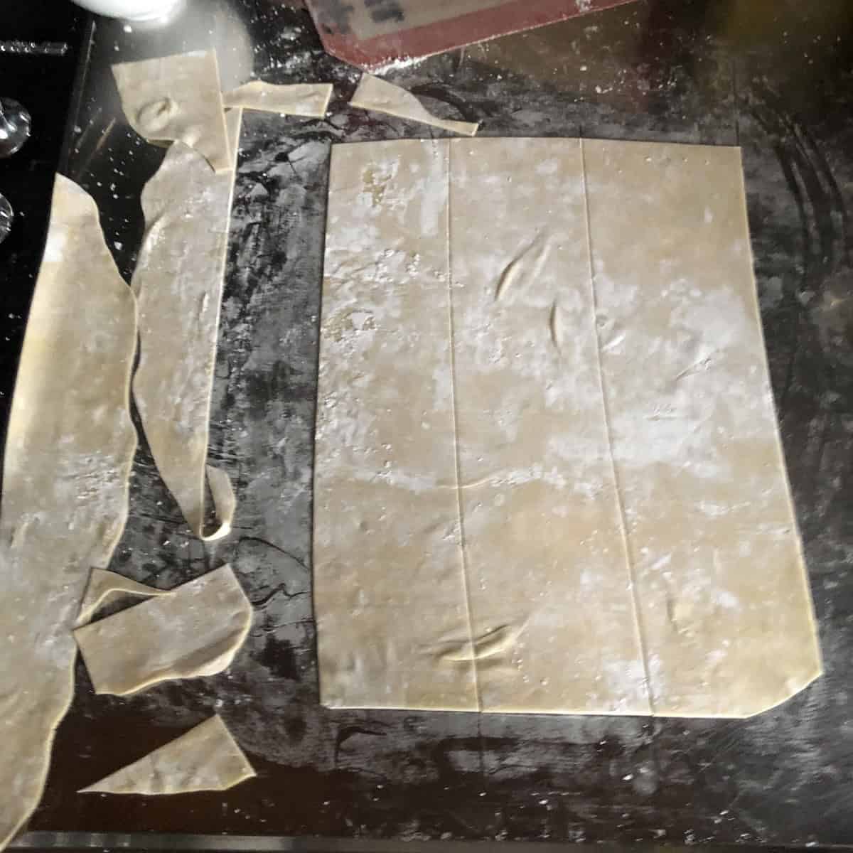 Using a pizza cutter to cut square wonton wrappers from rolled dough, wonton wrappers recipe for homemade wonton skins from scratch.