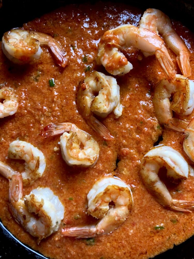 pan seared shrimp in a pan full of cream tomato alfredo