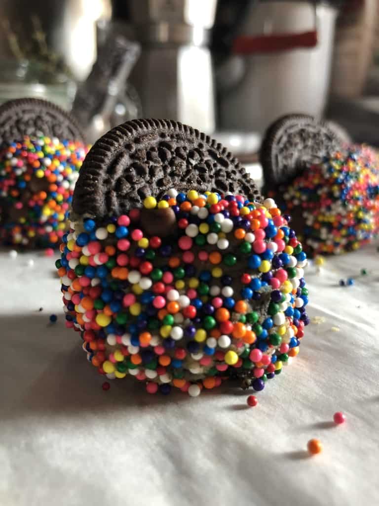 raw double oreo confetti cookies with halves of oreos in each cooking sticking out in a way that looks like it's in the cookie's back pocket about to be baked