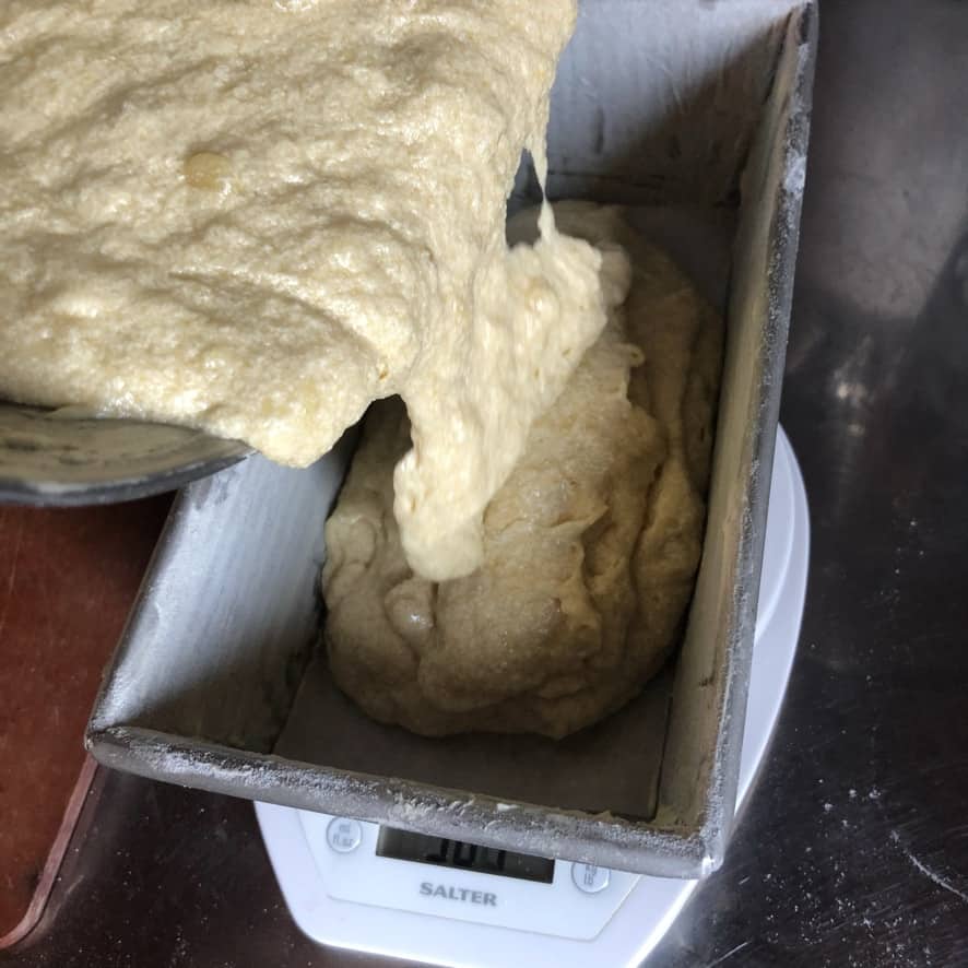 banana bread batter being poured into a prepared (buttered and floured) loaf pan