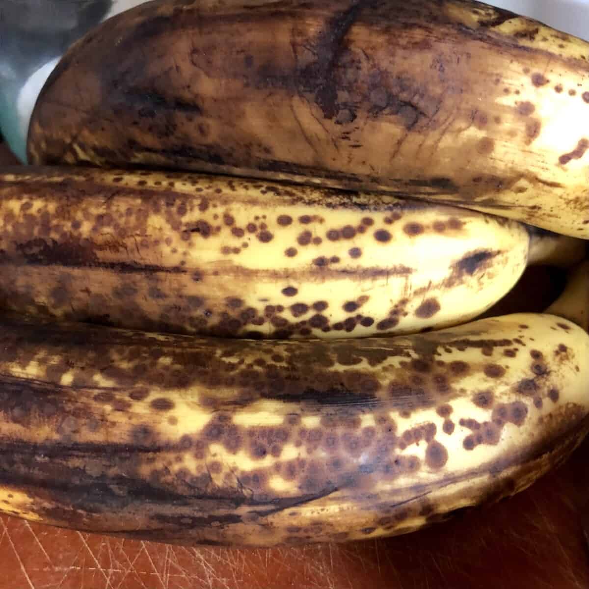 3 overly ripe black and brown-spotted bananas closeup