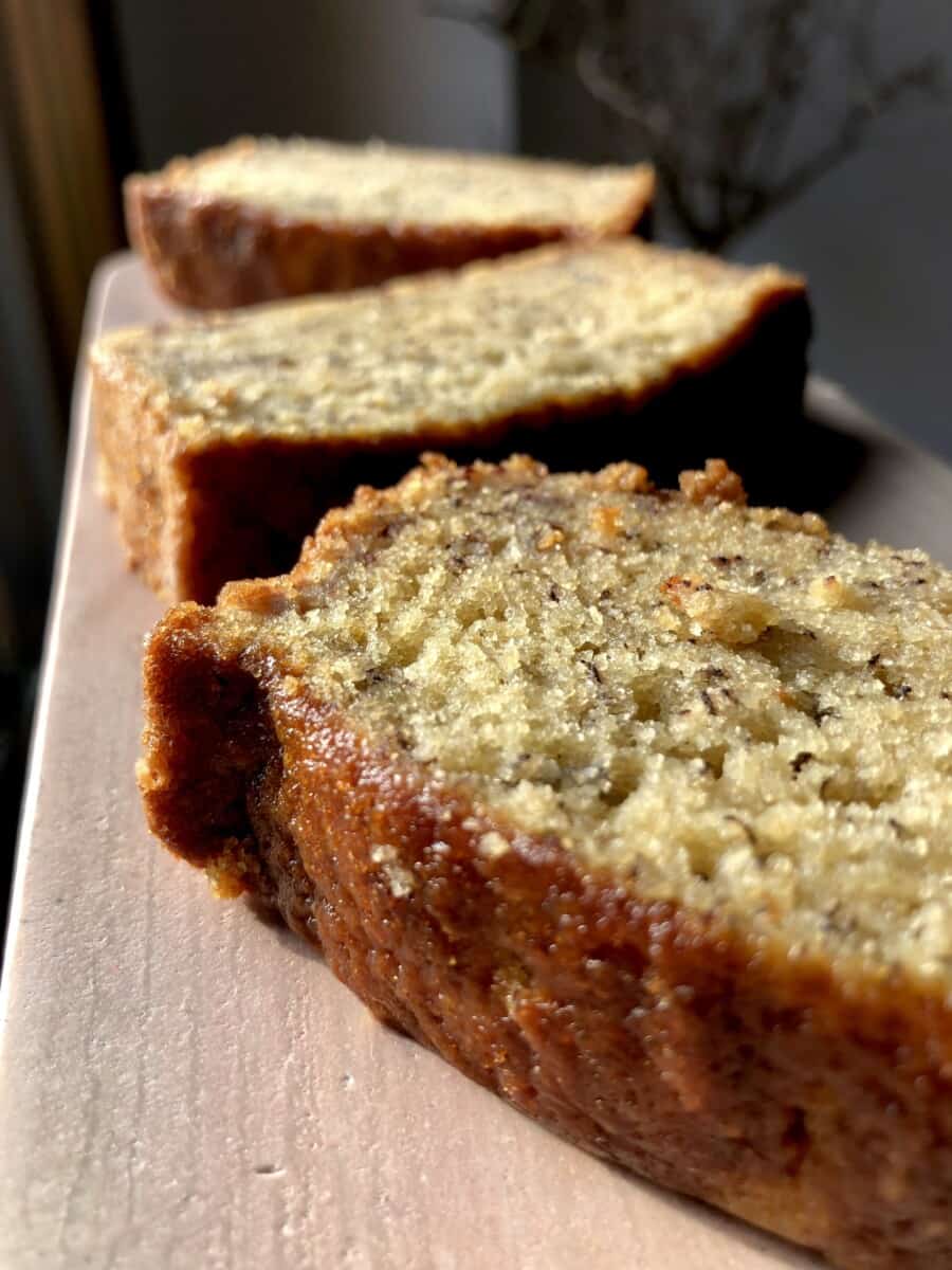 slices of banana bread cake on a pink marble serving tray with the sunlight hitting it