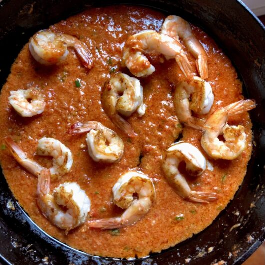 pan seared shrimp in a pan full of creamy tomato alfredo