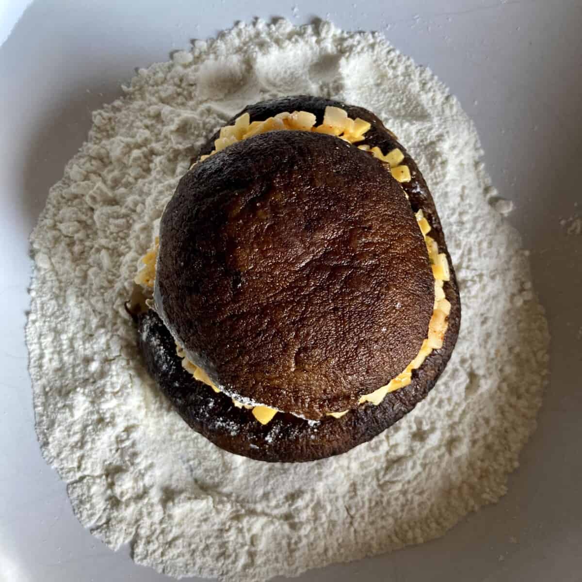 cheese stuffed portobello mushroom in a bowl of flour