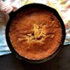 a cast iron skillet with a golden brown cherry cobbler baked beautifully and the sunlight hitting it