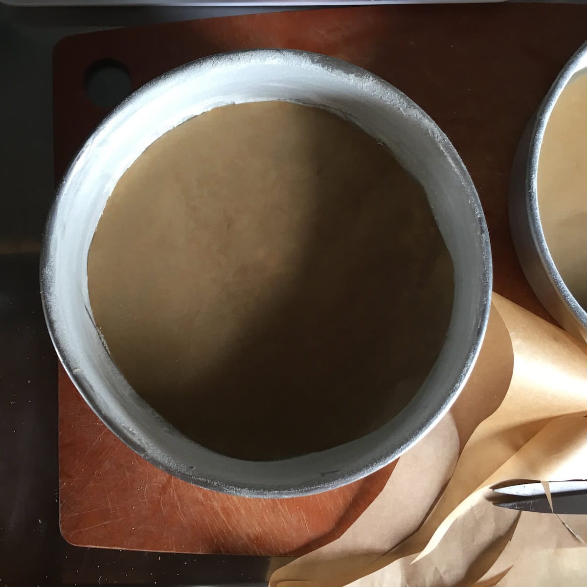Buttered and floured cake pans with fitted parchment rounds in the bottoms, the best way to guarantee a perfect release for a homemade carrot cake from scratch.
