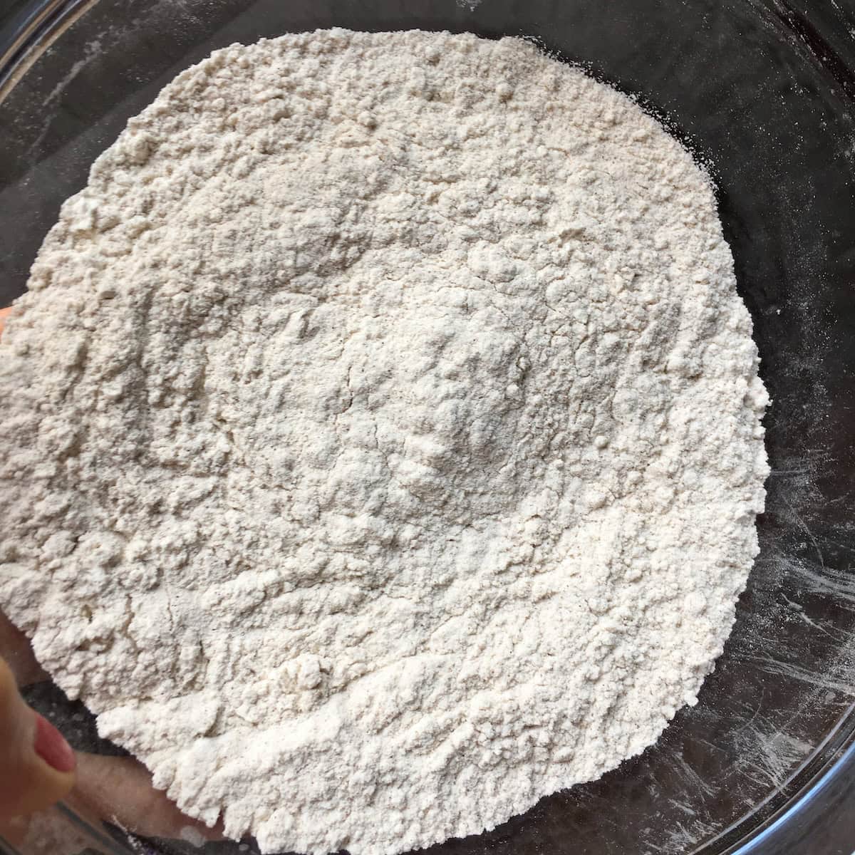 Whisked dry ingredients in a bowl for an easy carrot cake recipe from scratch, including flour, baking soda, cinnamon, and salt.