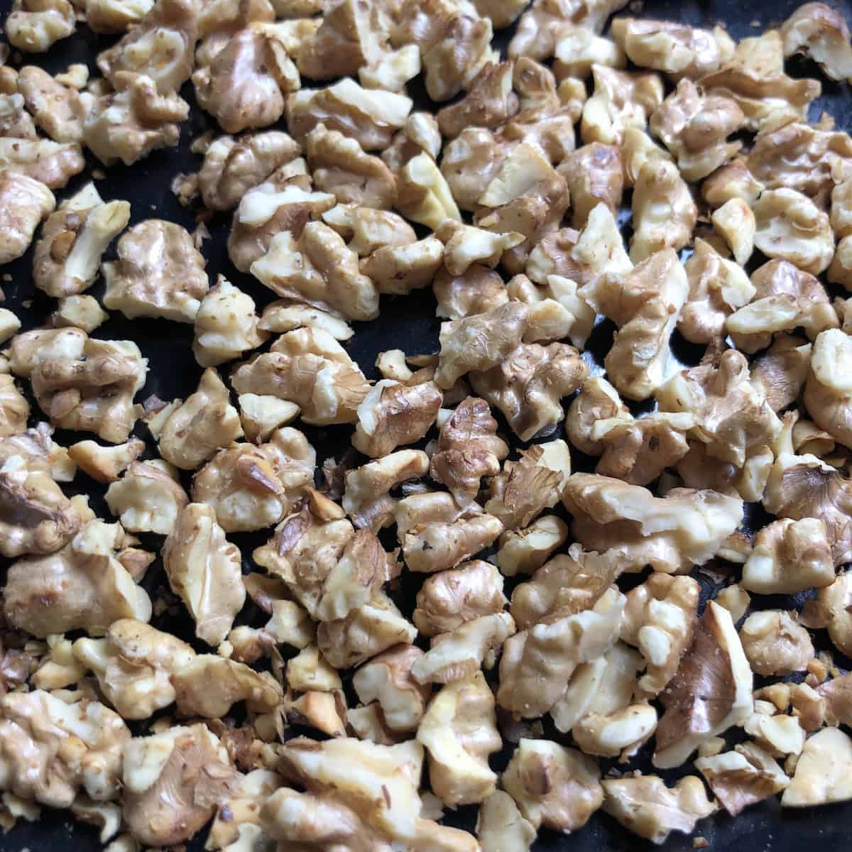 Walnut halves on a sheet pan ready to toast for a homemade carrot cake recipe with walnuts.
