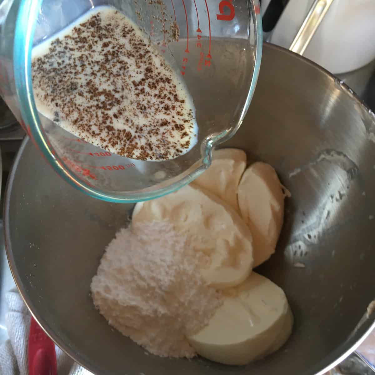 Sifted powdered sugar, cream cheese, milk, vanilla extract, and vanilla bean powder in a stand mixer bowl before combining for a butter cream cheese frosting and carrot cake cream cheese icing.
