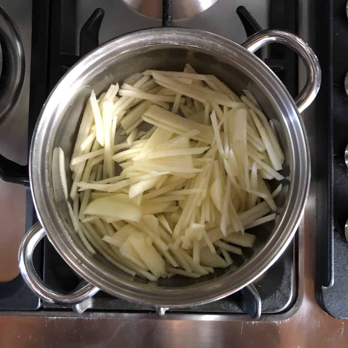 Pot of finely julienned apple ready to cook down into homemade applesauce to make a substitute applesauce for oil in carrot cake for a lighter, moister, more tender crumb.