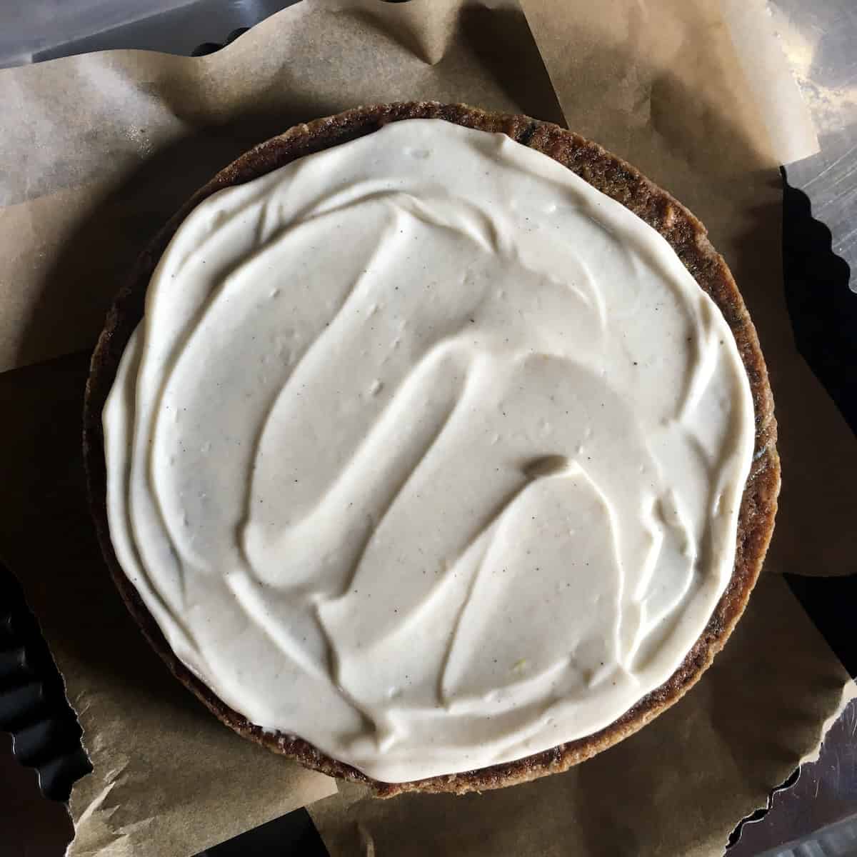 A fully frosted purple carrot cake bottom layer with cream cheese frosting, ready for the second layer - the best carrot cake recipe ever built one layer at a time.