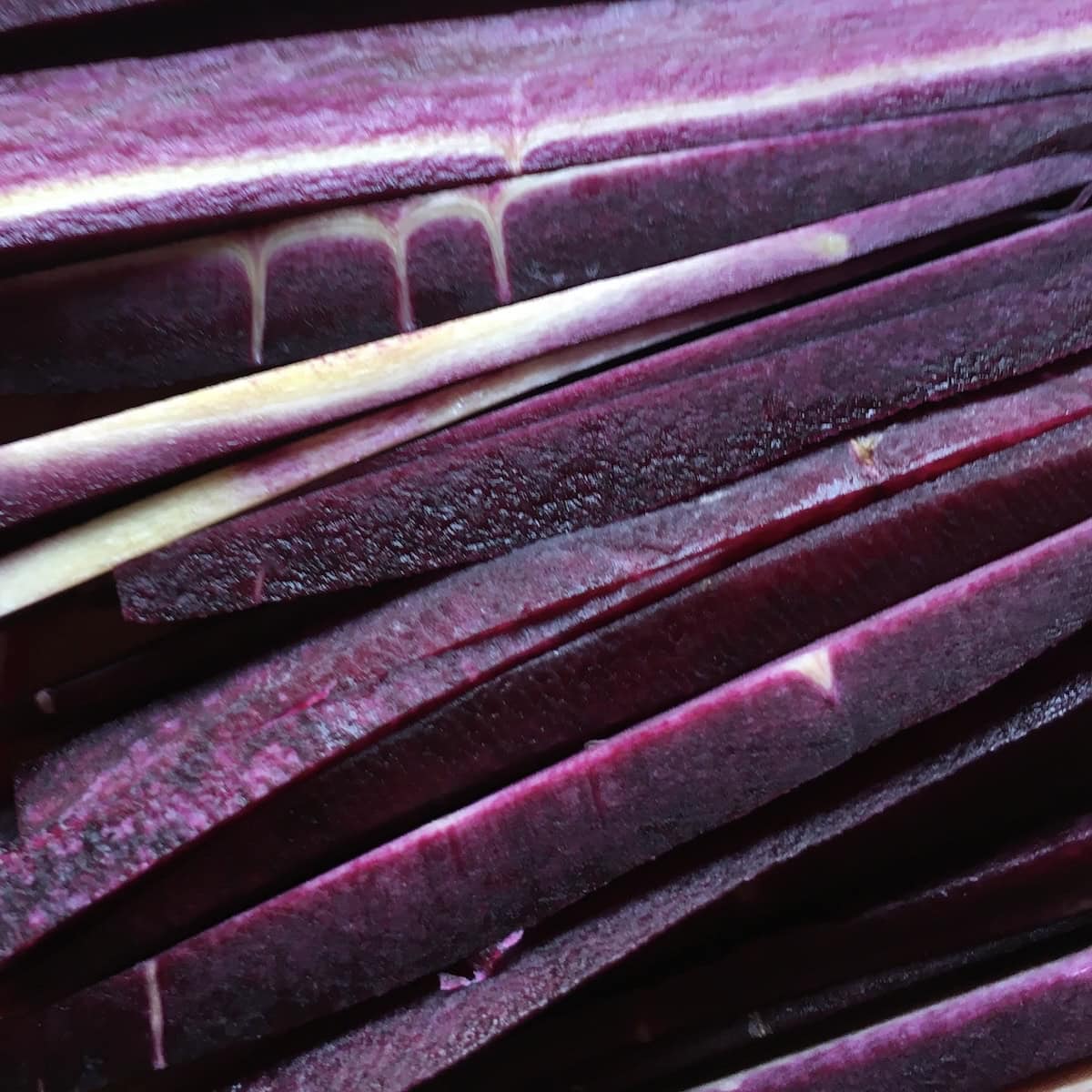 Peeled and sliced purple carrots showing their deep purple interior with white centers - cosmic purple carrot nutrition and benefits packed into every slice, and a stunning addition to carrot cake.