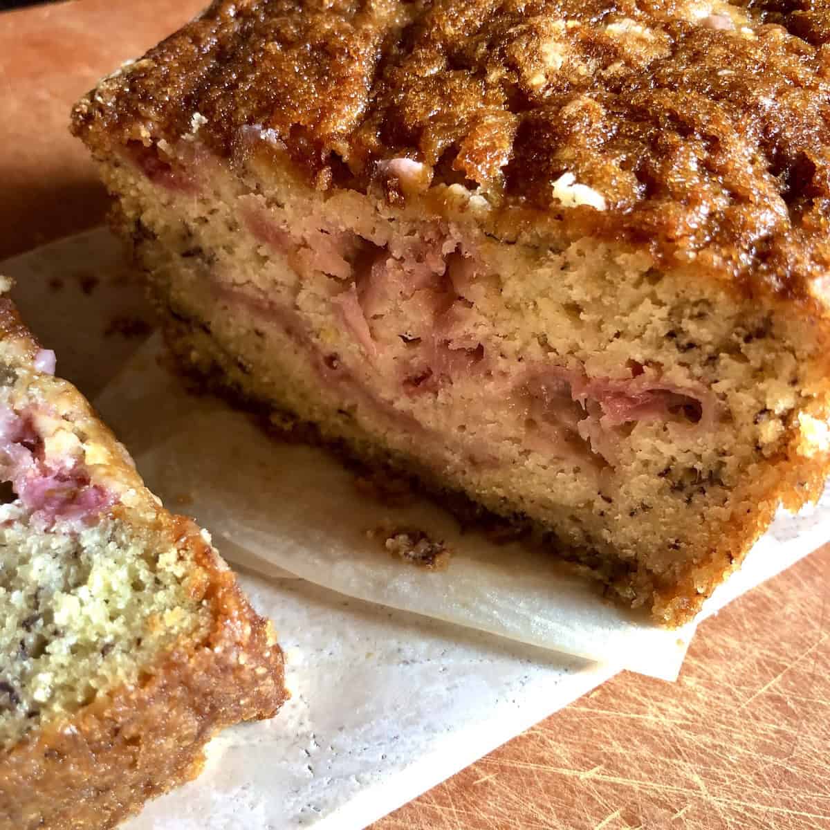 Sliced strawberry banana bread showing pink pockets of fresh strawberries throughout the moist crumb.
