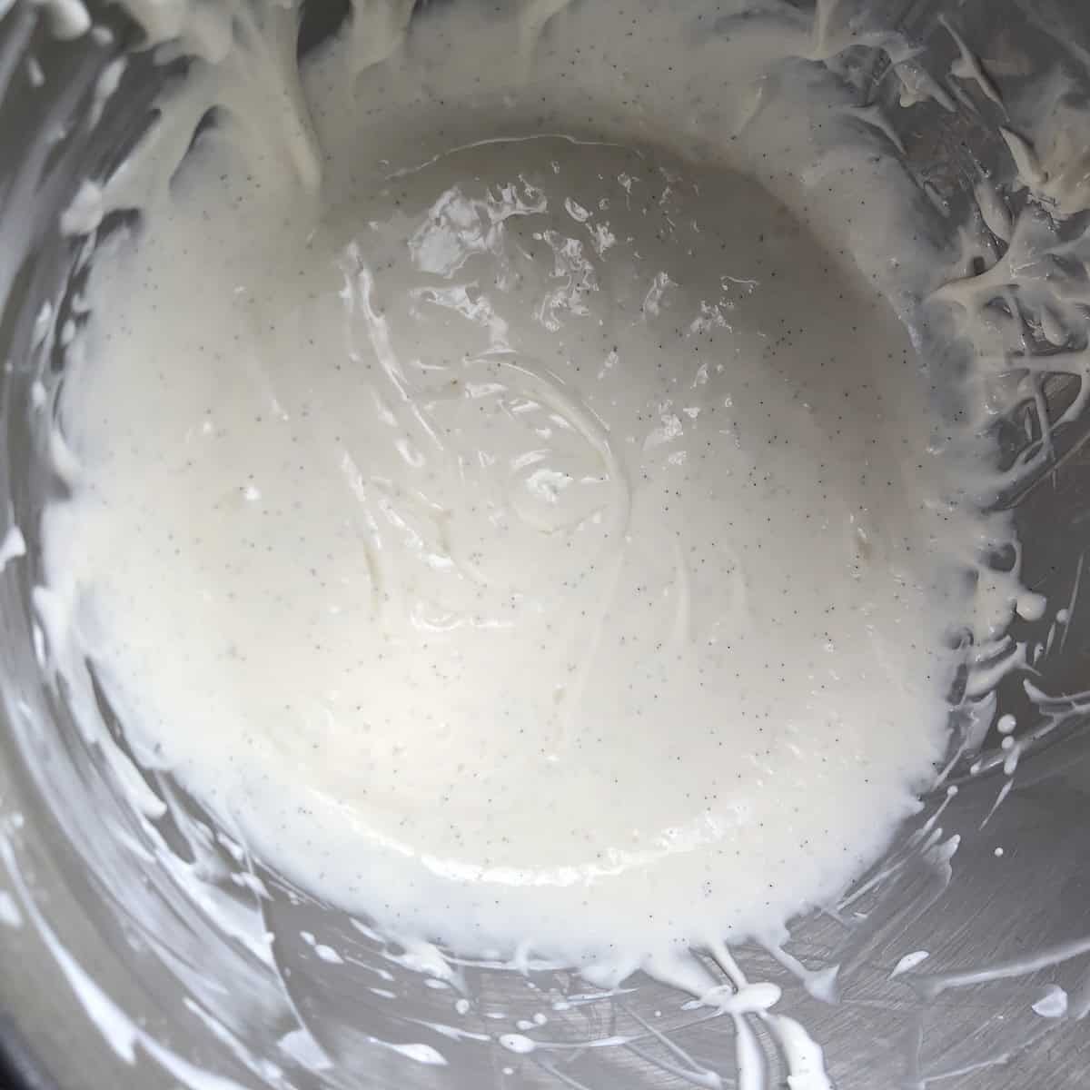 A stand mixer bowl of fully incorporated vanilla bean cream cheese frosting, smooth and flecked with vanilla bean for the best buttercream cream cheese frosting for carrot cake.
