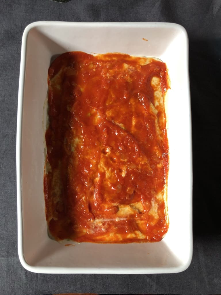 smoothed out tomato passata sauce in a casserole dishe