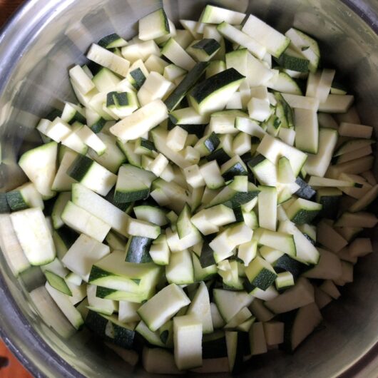 diced zucchini added to a pot with olive oil and a single blistered garlic clove