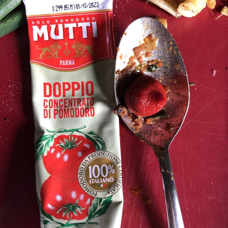 tomato paste squeezed out onto a spoon.
