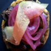 an open-faced grilled beef shortib chopped sandwich with smokey pickled red onions and a twisted lemongrass dill pickled watermelon ribbon on top