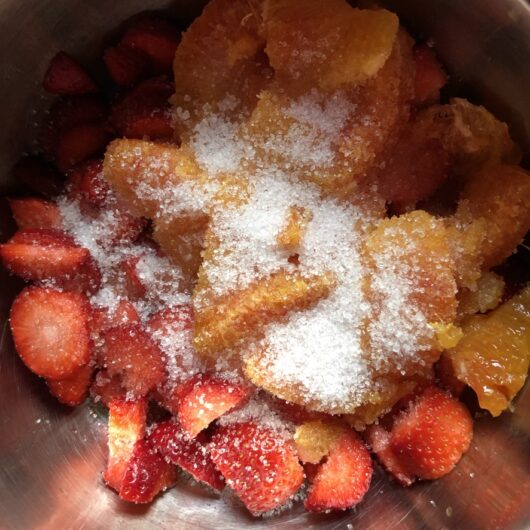 blood orange segments, strawberries, and sugar in a small pot